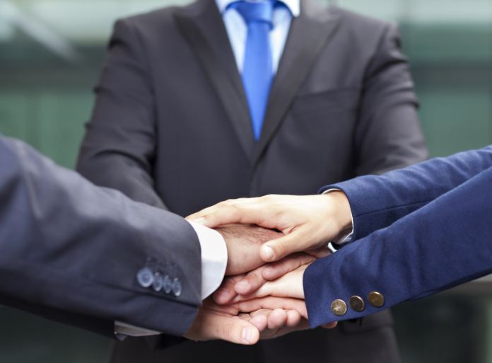 three people in suits shaking hands teamwork