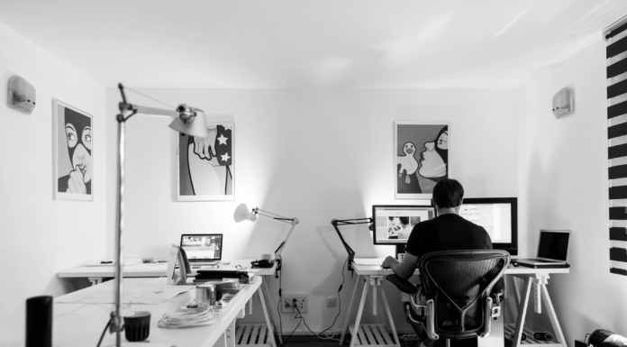 man sitting alone in office with computer black and white