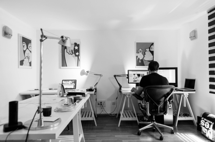 man sitting alone in office with computer black and white