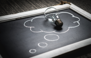 light bulb laying on chalk board with thought bubble