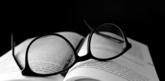 glasses laying on open book with black back round