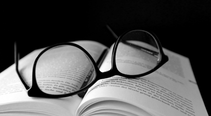 glasses laying on open book with black back round