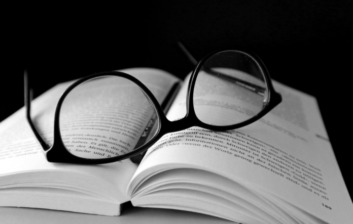 glasses laying on open book with black back round