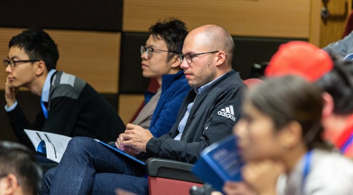 man with bald head and glasses sits in college room