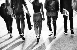 five friends walking carrying skate boards black and white photo