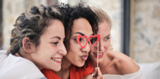 three women smiling and posing for camera with glasses prop