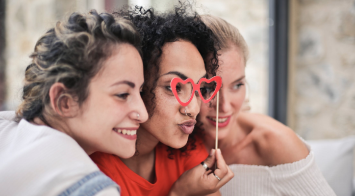 three women smiling and posing for camera with glasses prop