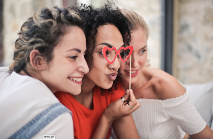 three women smiling and posing for camera with glasses prop