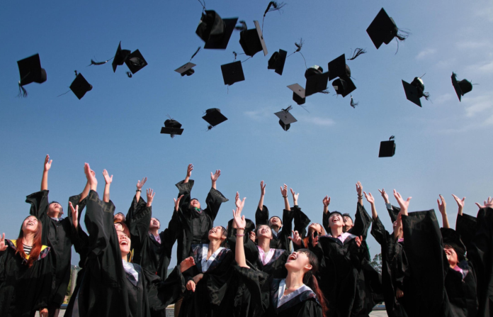 people at graduation throwing their caps in the air