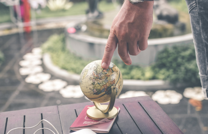 man pointing at little globe on wood table