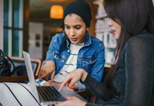 diverse women holding laptop talking