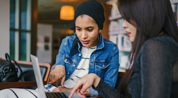 diverse women holding laptop talking