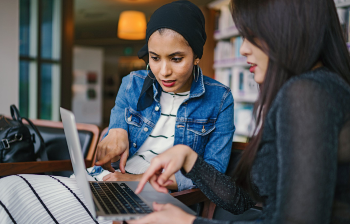 diverse women holding laptop talking