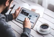 man on tablet doing business work at table with coffee mug