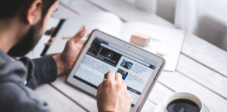 man on tablet doing business work at table with coffee mug