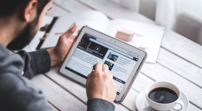 man on tablet doing business work at table with coffee mug