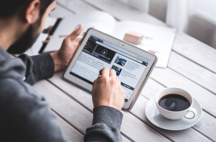 man on tablet doing business work at table with coffee mug